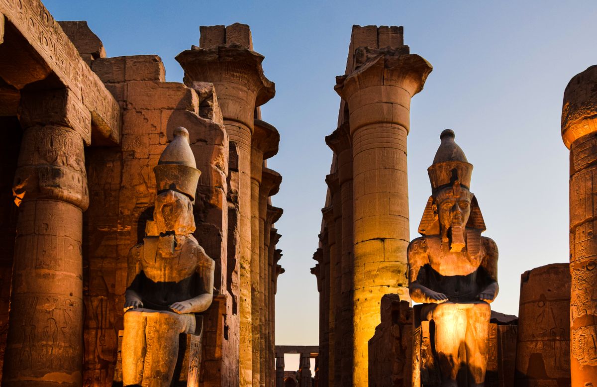 Verlichte beelden van Ramses II in de Luxortempel bij avond