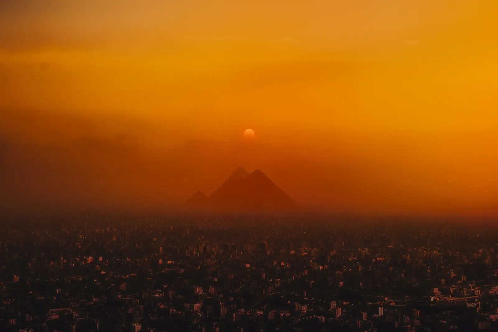 De piramides van Gizeh als silhouet boven Caïro bij zonsondergang